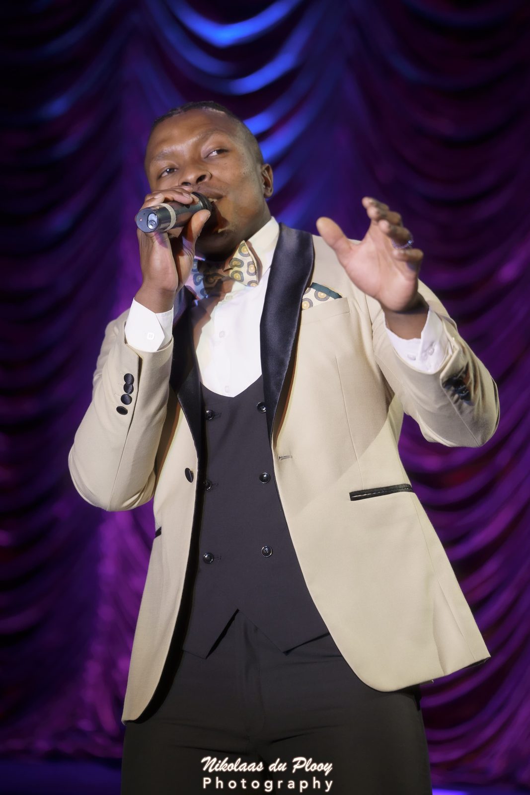 Thuba Myeki performing in a cream tuxedo