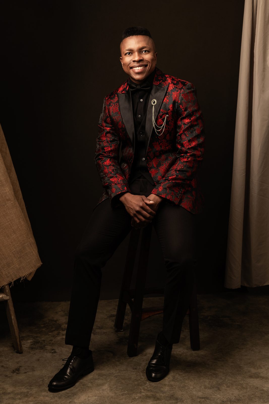 Thuba Myeki standing in a red brocade jacket
